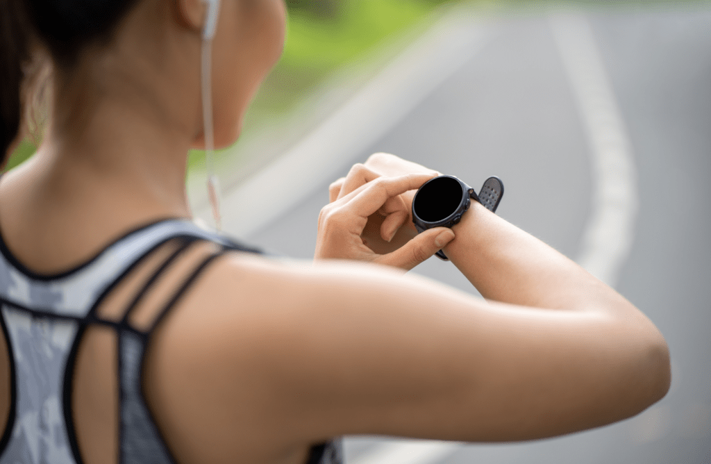 Person mit Smartwatch am Handgelenk, die Trainings- oder Gesundheitsdaten während sportlicher Aktivität überprüft