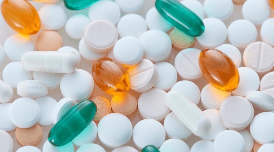 Verschiedene Tabletten und Kapseln auf hellem Hintergrund als Symbol für Wechselwirkungen zwischen Supplementen und Medikamenten.