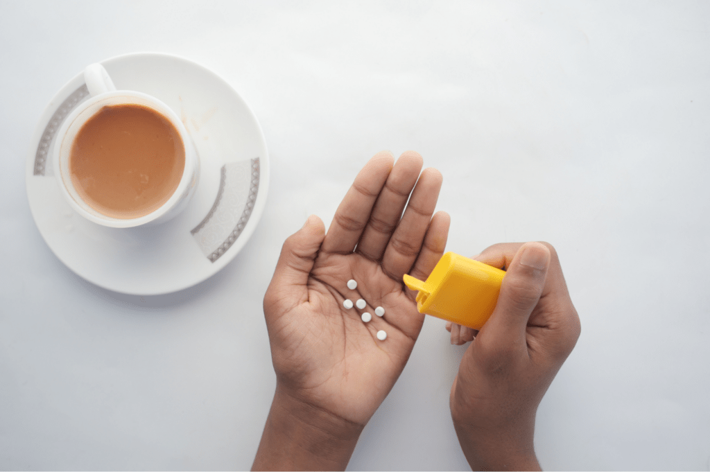 Süßstofftabletten in der Hand neben Kaffee als Beispiel für Süßstoffe beim Abnehmen.